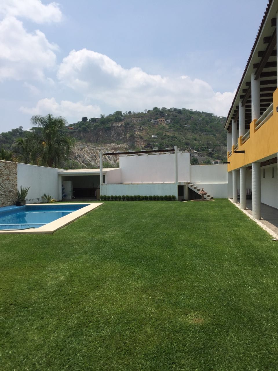 A modern building with a swimming pool and a well-maintained lawn.