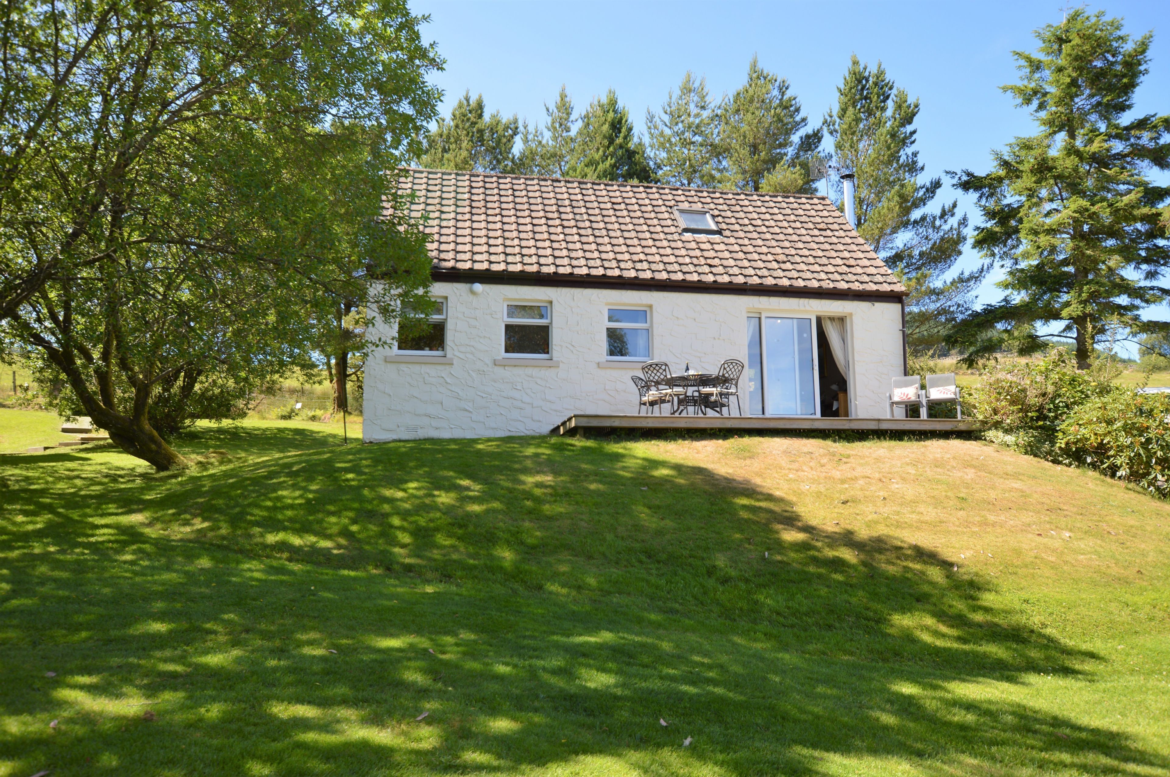 Een gelijkvloers huis met een pannendak, een klein portaaltje met een tafel en stoelen, en een deur die naar binnen leidt.