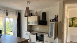Een moderne keuken met witte kasten, een inbouwoven en een magnetron.