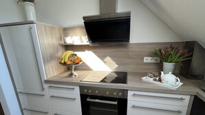 Een kleine keuken met een ingebouwde oven, een magnetron en een spoelbak.