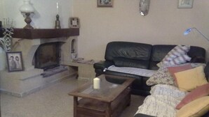 Ein Wohnzimmer mit Kamin, einem grünen Sofa, einem Holztisch und einer Lampe.