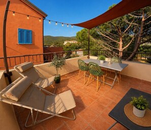 Eine Terrasse im Freien mit Tisch und Stühlen, einer Couch und einem Blumentopf.