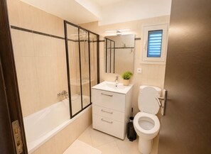 Une salle de bain moderne équipée d’une baignoire, de toilettes, d’un lavabo et d’un espace douche.