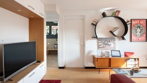 Ein modernes Wohnzimmer mit Flachbildfernseher, einem roten Sofa, einem Holzschrank und einer Wanduhr.
