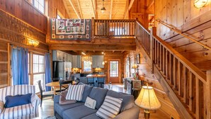 A spacious wooden cabin with a loft bedroom, a dining area, and a kitchen. - Walk in the Clouds - Rustic Cabin with Hot Tub, Outdoor fireplace, Fenced Dog Area (Boone)