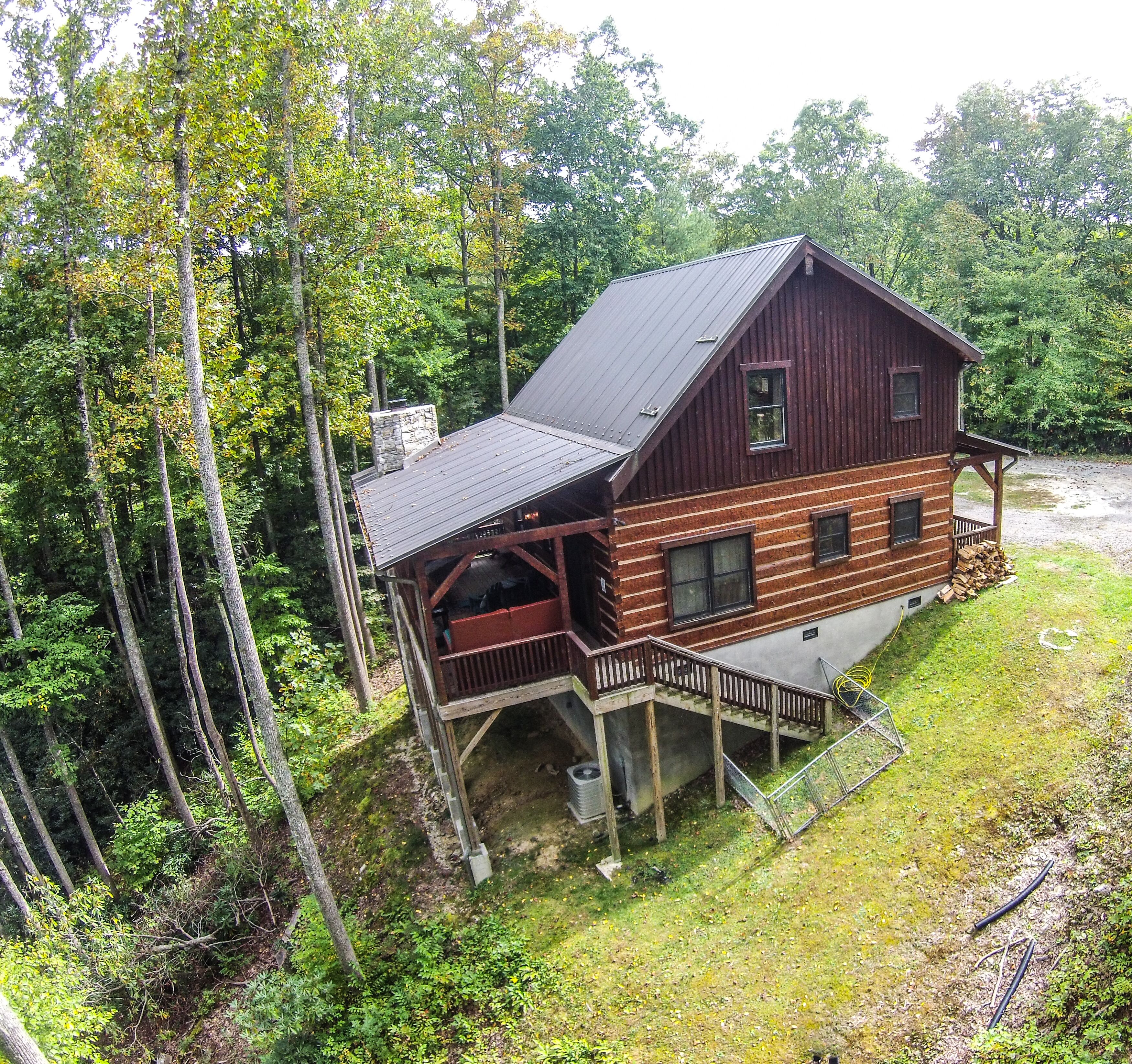 A cabin with a wooden exterior, a porch, and a chimney.
