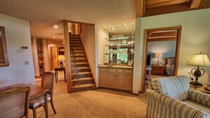 Un interior acogedor con una escalera, armarios de madera, un comedor y una sala de estar con sofá y lámpara.