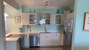 A kitchen with white cabinets, a stainless steel refrigerator, and a dishwasher. - Salty dog on the rocks (Port St Joe)