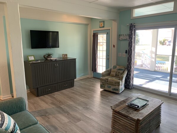 A living room with a TV, a cabinet, a chair, and a coffee table. - Salty dog on the rocks (Port St Joe)