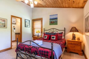 A bedroom with a bed, a nightstand, a lamp, and a window with blinds. - Almost Heaven: Pet-Friendly Cabin with Yard and Hot Tub in Valle Crucis - Walk to River (Sugar Grove)