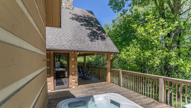 Een houten terras met een jacuzzi, een overdekte zithoek en een stenen muur.