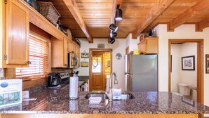 A kitchen with wooden cabinets, a stainless steel refrigerator, a coffee maker, and a sink.