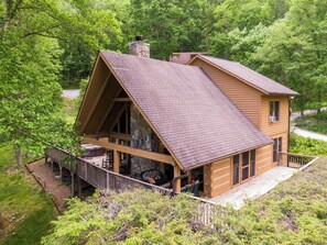 A cabin with a stone chimney, wooden deck, and a large window. - Almost Heaven: Pet-Friendly Cabin with Yard and Hot Tub in Valle Crucis - Walk to River (Sugar Grove)