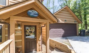 A lodge entrance with a wooden facade, a welcome sign, a garage, and a sign reading "Almost Heaven". - Almost Heaven: Pet-Friendly Cabin with Yard and Hot Tub in Valle Crucis - Walk to River (Sugar Grove)
