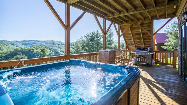 Un jacuzzi en una terraza de madera con vistas a un paisaje boscoso.