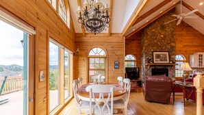 Interior de madera con una mesa de comedor, sillas, una chimenea y una pared de piedra.