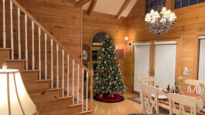 Interior de madera con una escalera, un árbol de Navidad y un comedor.