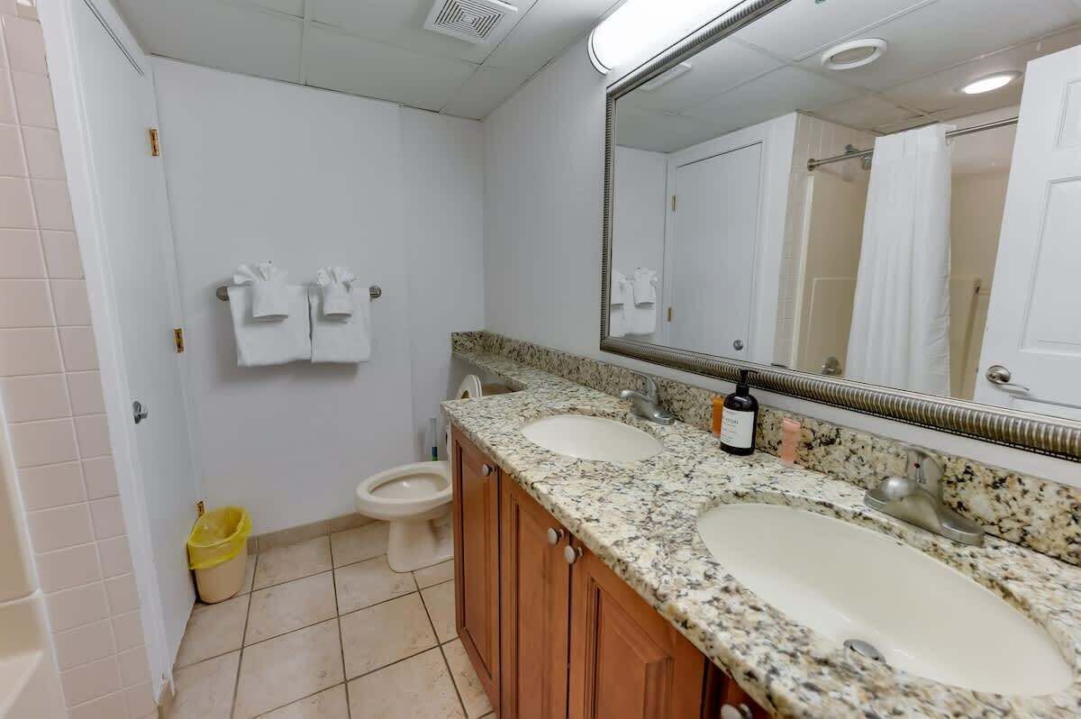 A bathroom with two sinks, a toilet, and a mirror.