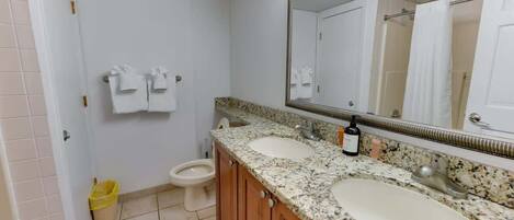 A bathroom with two sinks, a toilet, and a mirror.