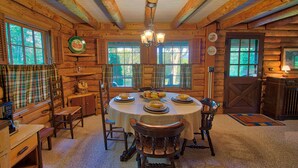 Un comedor rústico de madera con una mesa redonda dispuesta para cuatro comensales, flanqueada por sillas de madera.
