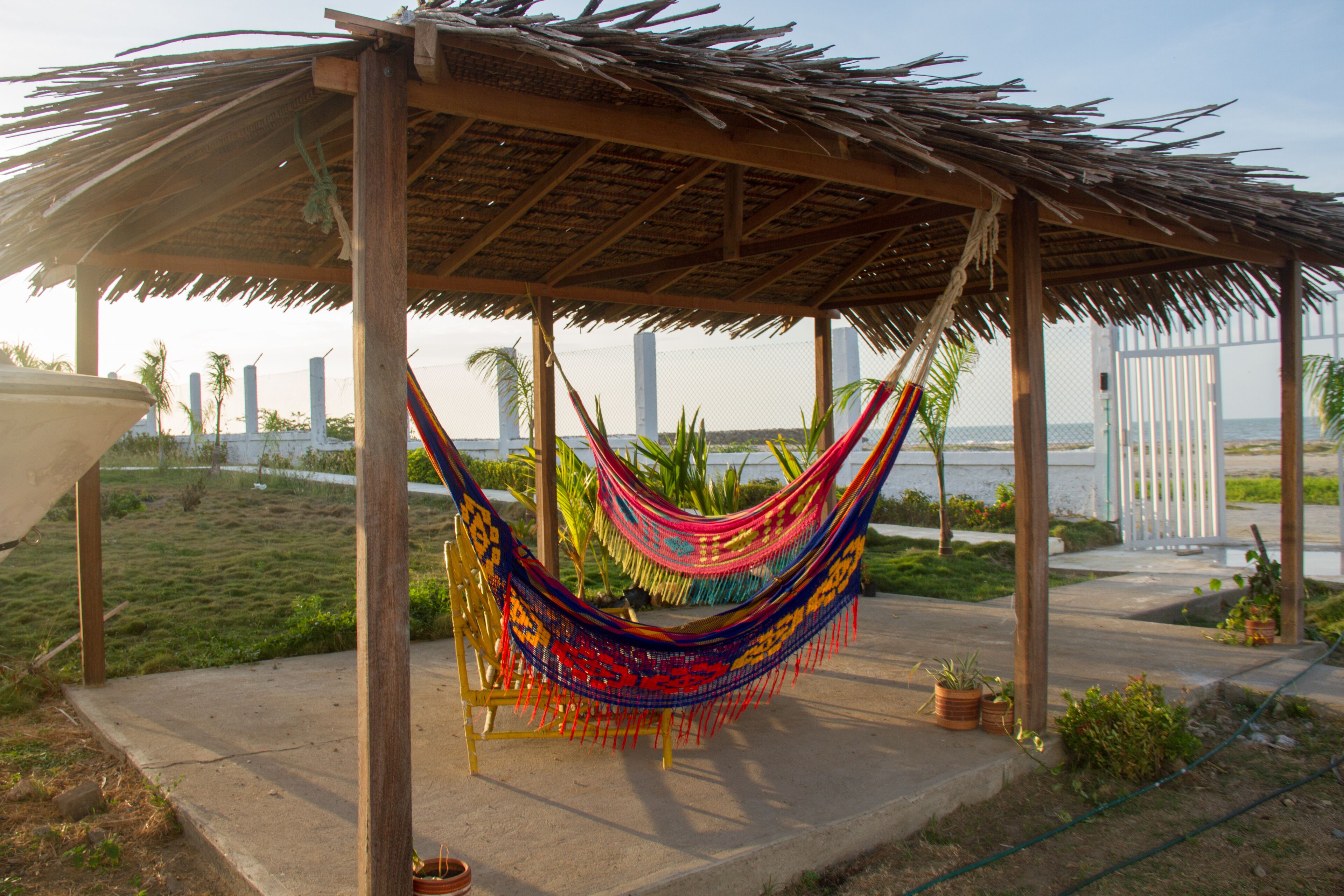 A thatched-roof gazebo with a colorful hammock.