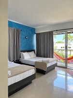 Habitación de hotel con dos camas, un ventanal grande y vistas a palmeras.