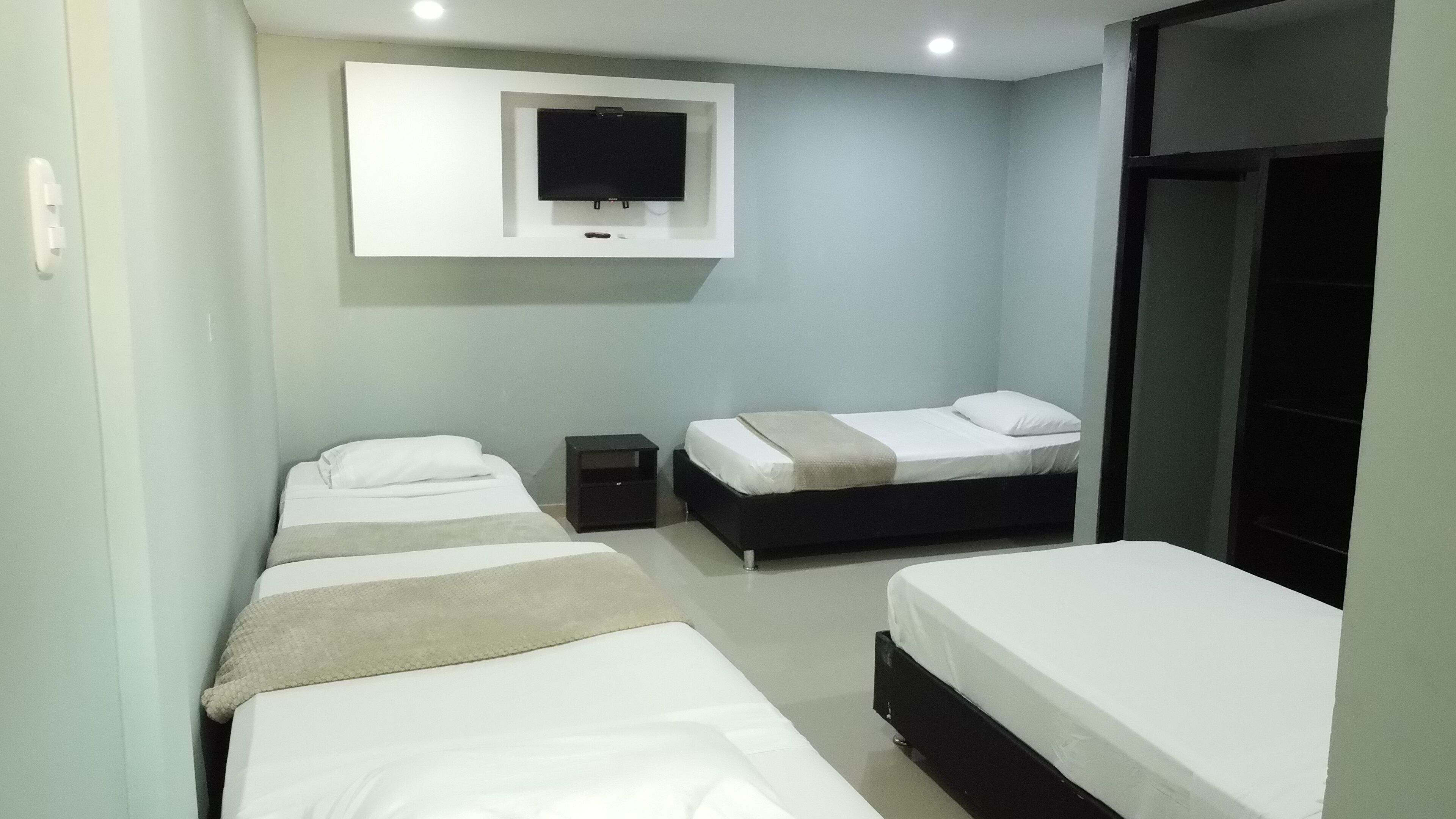 A hotel room with two single beds, a TV mounted on the wall, and a wardrobe.