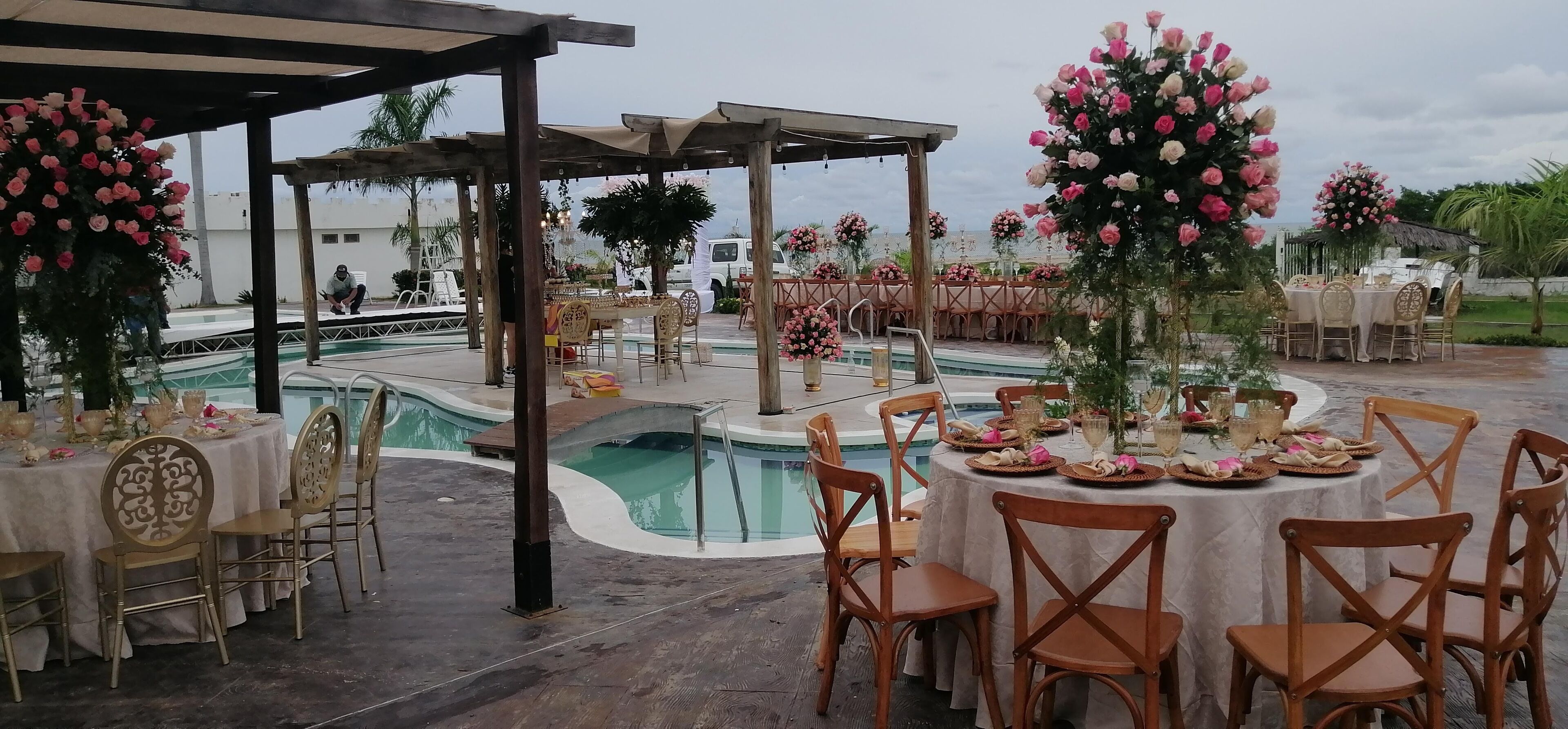 An outdoor event space with round tables, chairs, and floral centerpieces.