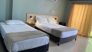 Quarto de hotel com duas camas, uma cabeceira de madeira, luminárias de cabeceira e um ar condicionado.