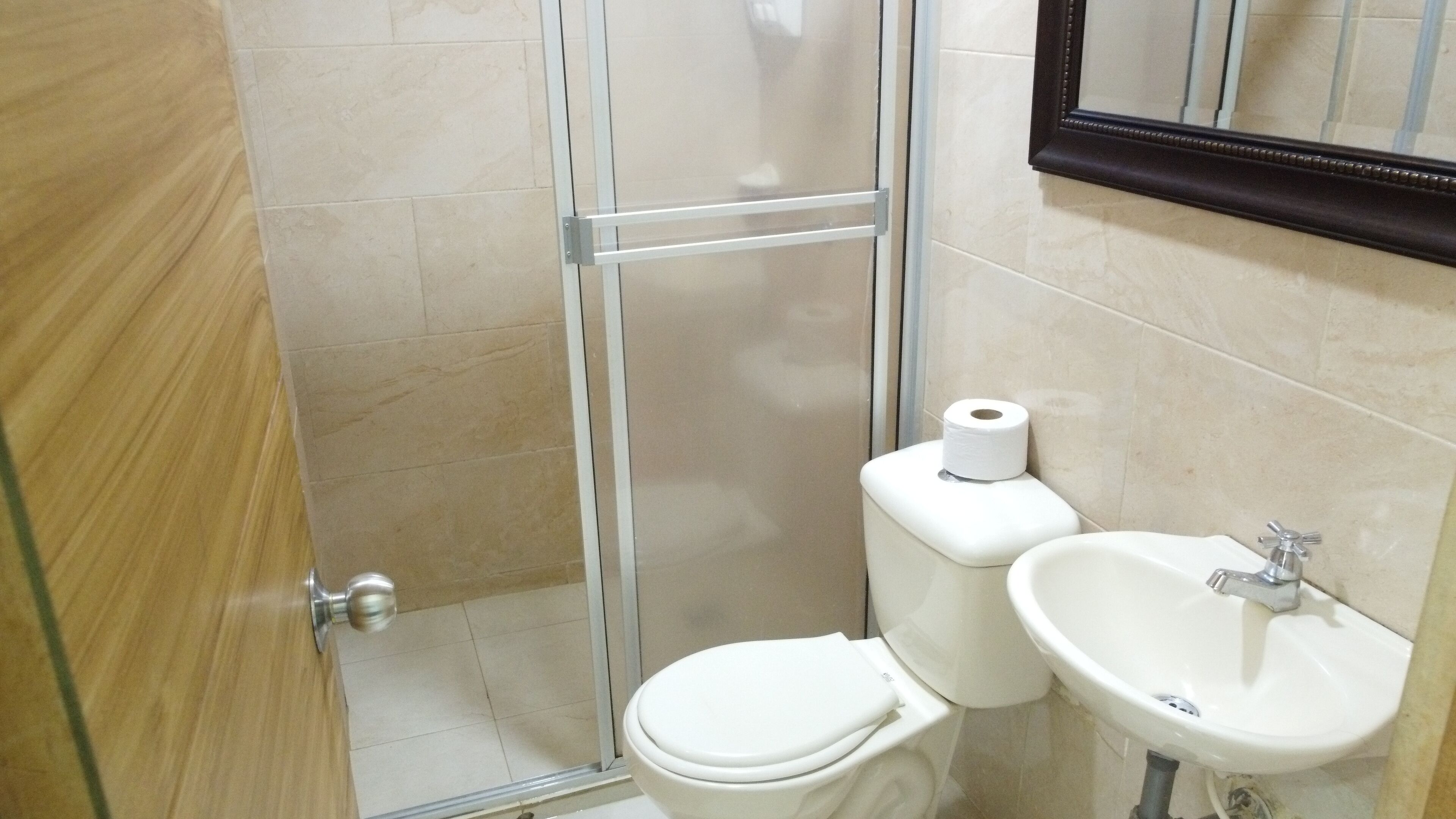 A bathroom with a glass shower enclosure, a toilet, and a sink.