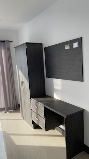 A modern room with a dark wooden desk, a wardrobe, and a wall-mounted TV.