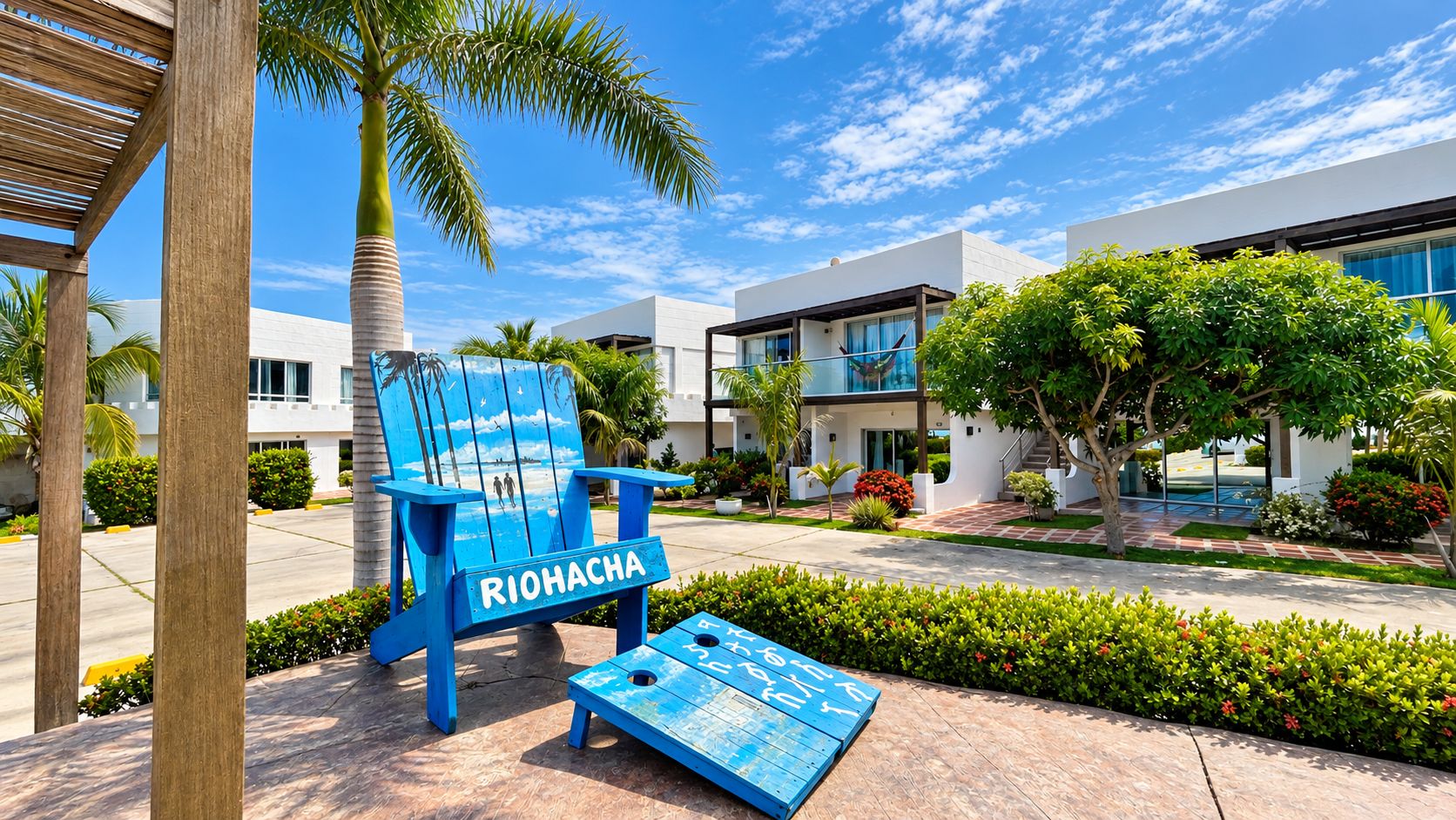 Ein blauer Stuhl mit der Aufschrift 'RIOHACHA', ein modernes Gebäude und ein gepflegter Garten.