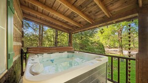 Un bain à remous situé sur une terrasse en bois, avec vue sur les arbres.