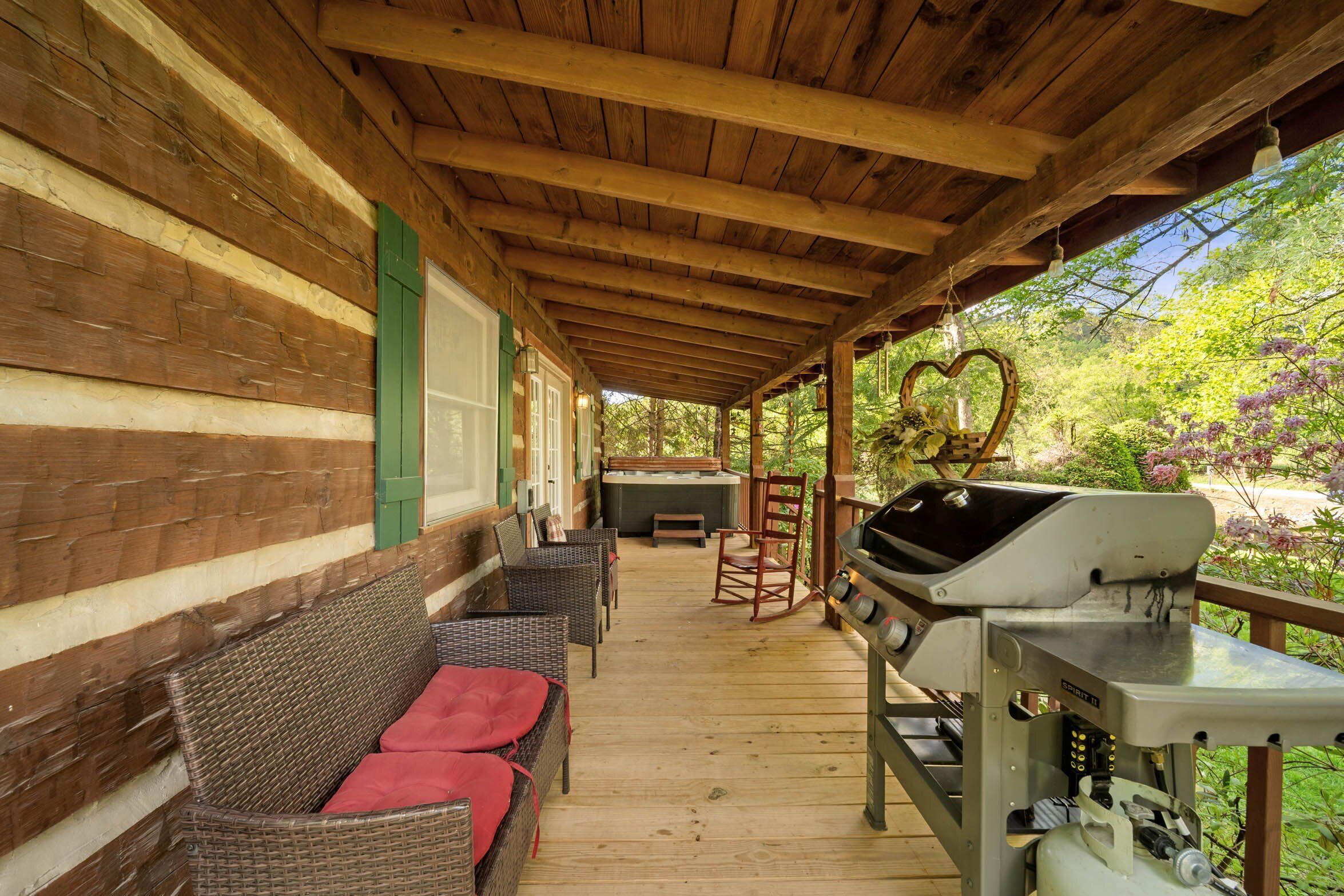 A covered porch with wicker furniture and a grill.