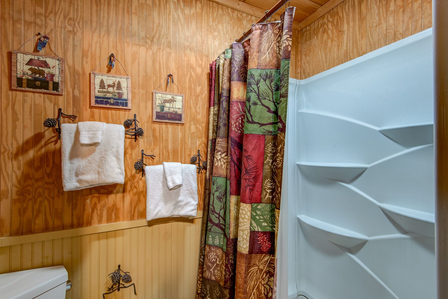 Cozy cabin charm carries right into the bathroom, with warm wood paneling and playful pinecone accents throughout.