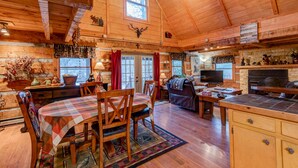 Un intérieur de chalet chaleureux comprenant un coin repas, un salon et une cuisine.