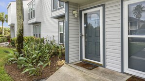 A two-story residential building with a front door, a small porch, and a mailbox.
