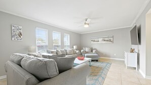 A living room with a grey sofa, a coffee table, and a TV on a stand.