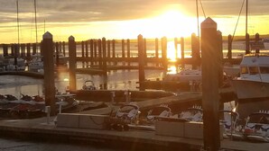 A marina with boats docked, a wooden pier, and a sunset in the background.