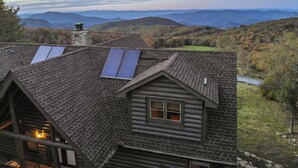 A log cabin with a sloped roof, two solar panels, and a view of the surrounding hills. - Highland Mist  Pet Friendly, Beautiful Views, Hot Tub, Game Tables, Winery Close by (Banner Elk)