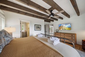Une chambre à coucher avec un lit, une commode, un ventilateur de plafond et un tableau.