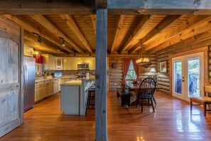 A log cabin interior with a kitchen, dining area, and large windows.