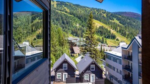 Blick aus einem Fenster auf eine gebirgige Landschaft mit Wald und Wohngebäuden.