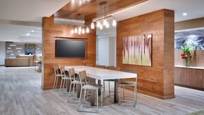 A modern conference room with a long table, chairs, a flat-screen TV, wooden panel walls, and a ceiling with exposed beams. - Fairfield by Marriott Inn & Suites Denver West/Federal Center (Lakewood)