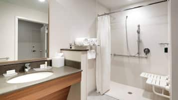 Un baño moderno con lavabo, espejo, ducha e inodoro.