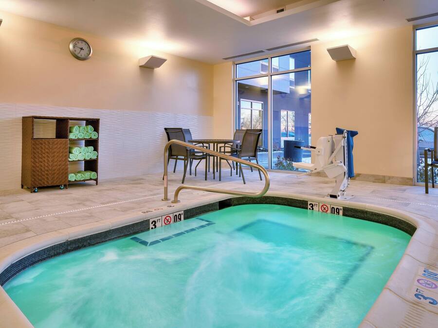 A hotel pool area with a seating area, a clock on the wall, and a view of the outdoors.