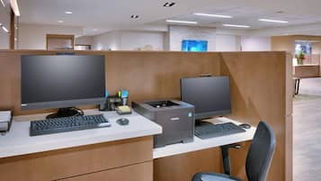 Un cubículo de oficina moderno con dos monitores, un teclado, un ratón e impresora Samsung.