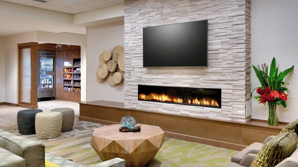 A modern living room with a flat-screen TV, a fireplace, and a coffee table. - Fairfield by Marriott Inn & Suites Denver West/Federal Center (Lakewood)