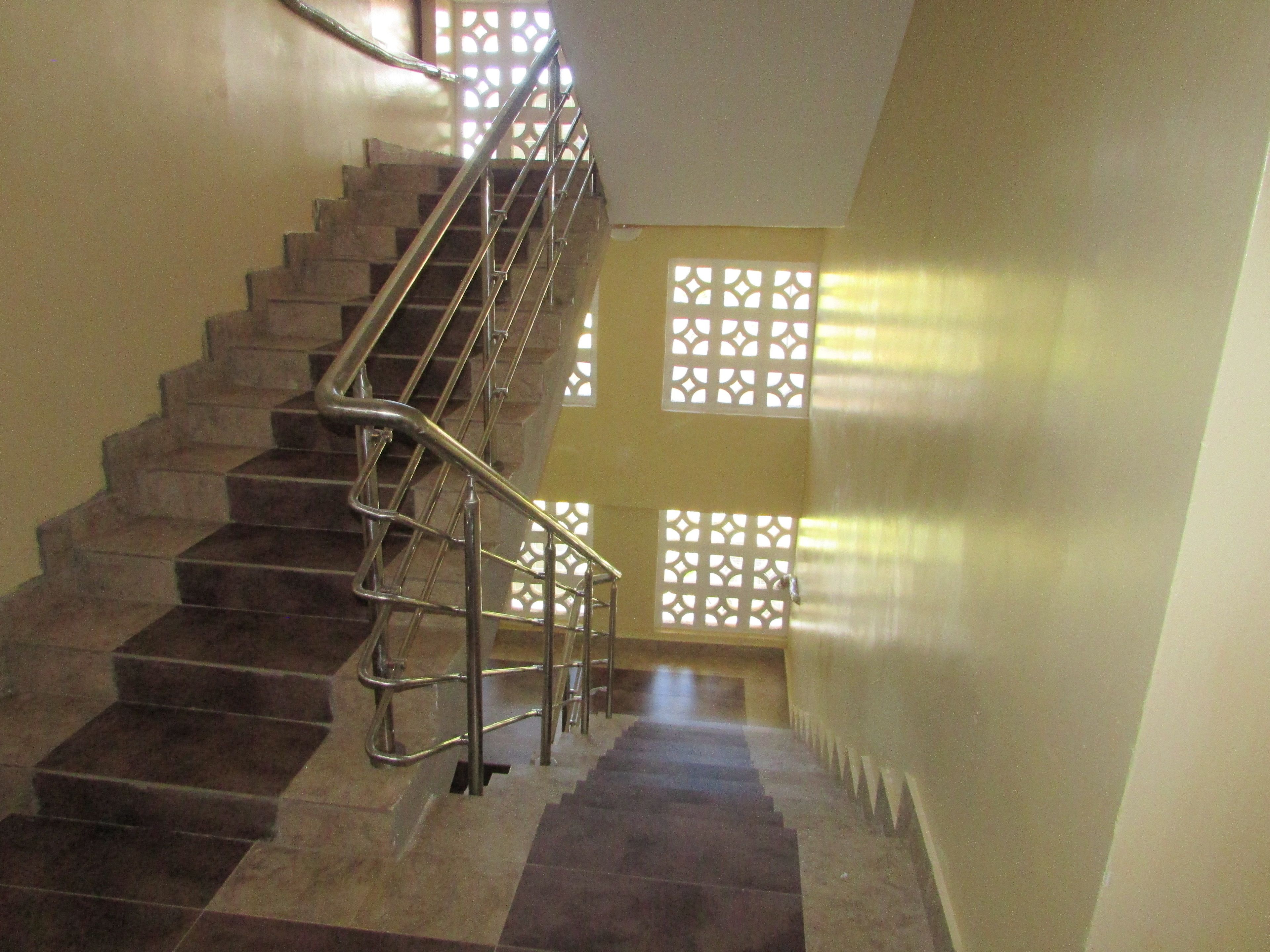 Una escalera con barandillas de metal y ventanas con diseño.