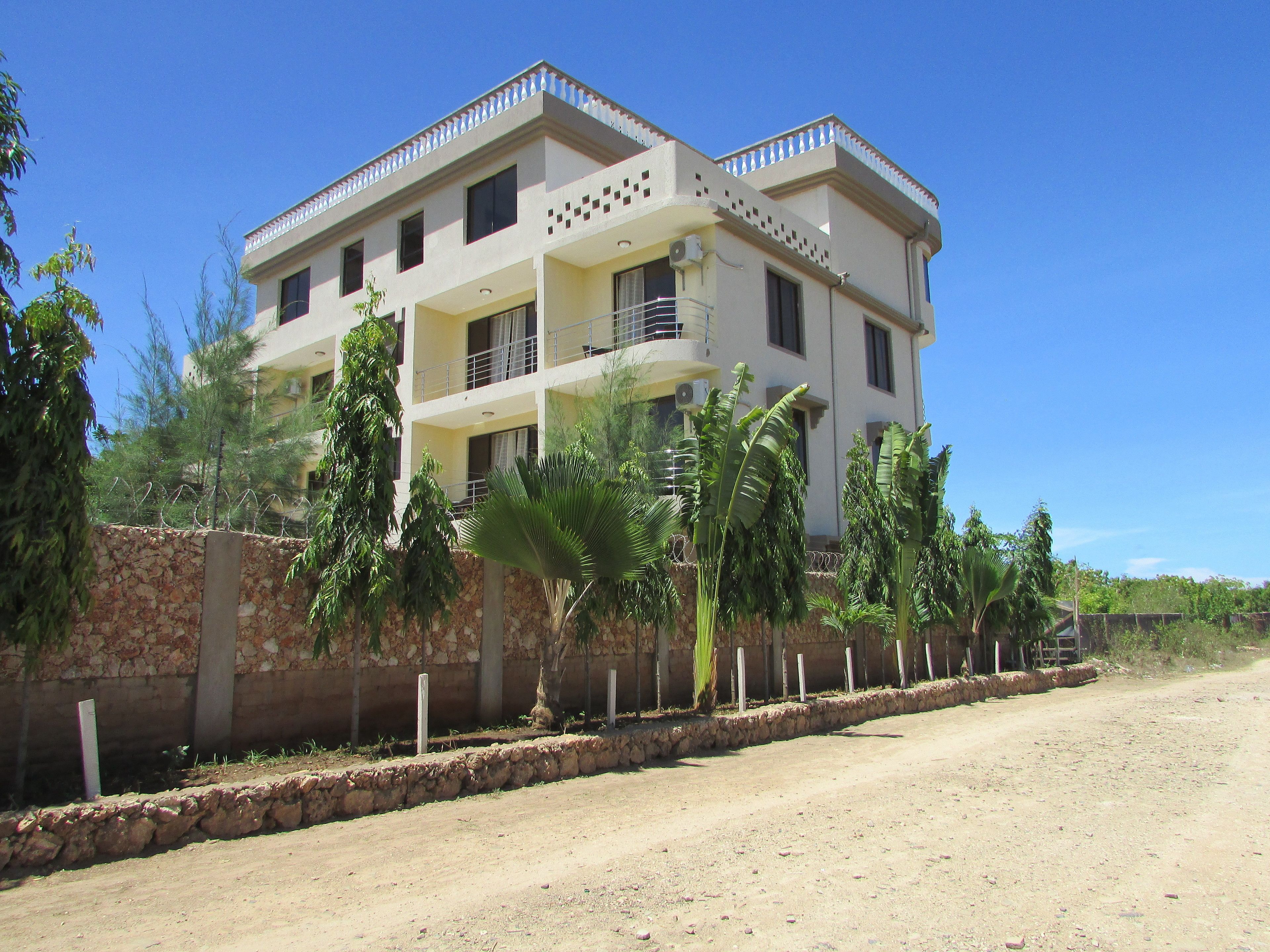 Un edificio de dos pisos con balcones y un muro de piedra.
